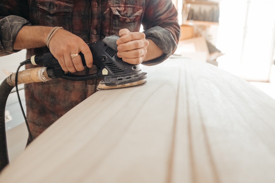 Pessoa lixando uma superfície de madeira MDF antes de aplicar tinta