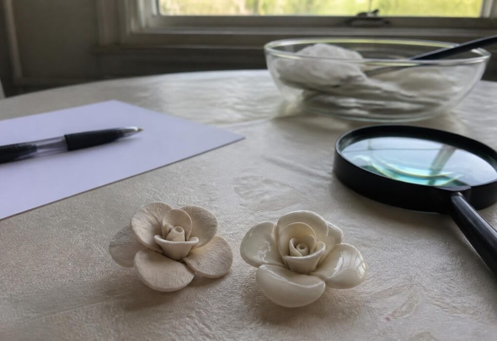 Duas flores de massa seca lado a lado sobre a mesa, com lupa e caderno de anotações